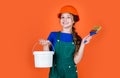 cheerful child laborer using building uniform and painting bucket and brush, creative work