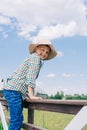 cheerful child in panama hat climbing on fence and smiling at camera Royalty Free Stock Photo