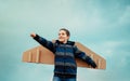 Cheerful child playing with paper wings airplane. Concept of tourism