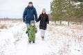 Cheerful child runs in the winter in the snow ahead, and his parents follow him. The family walks in winter