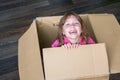 A cheerful child is sitting in a cardboard box. The little girl climbed into the postal box and laughs. The baby is smiling while Royalty Free Stock Photo