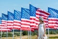 Child standing in white dress and straw hat near american flags