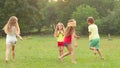 Cheerful children playing tag with clapping on the grass on a summer day. Slow motion