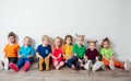 Cheerful children sitting on a floor near the wall Royalty Free Stock Photo