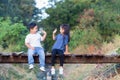 Cheerful children sitting on wooden bridge, Asian kids playing in garden, boy and girl reading books Royalty Free Stock Photo