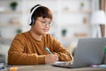 Cheerful korean boy schooler having online lesson from home