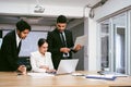 A cheerful and confident Asian businesswoman stands in the back of her office colleagues, presenting bar charts data. Royalty Free Stock Photo