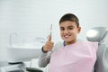 Cheerful confident brave handsome elementary aged child, school boy shows thumb up and smiles with beautiful toothy smile looking