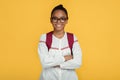Cheerful confident calm cute adolescent african american student girl in glasses with backpack with crossed arms