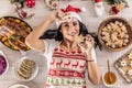 A cheerful cook in a Christmas apron is lying on the ground holding a Linzer pastry and a gingerbread star surrounded by Royalty Free Stock Photo