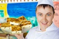 Cheerful cook holding cheese baked pudding on dish