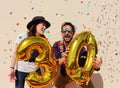 Cheerful couple celebrates a thirty years birthday with big golden balloons