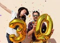 Cheerful couple celebrates a thirty years birthday with big golden balloons