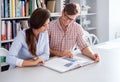 Cheerful couple of engineers having fun reading a book in a architect studio. Royalty Free Stock Photo