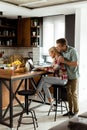 Cheerful couple enjoys a light-hearted moment in their sunny kitchen, working on laptop surrounded by a healthy breakfast Royalty Free Stock Photo