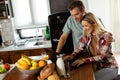 Cheerful couple enjoys a light-hearted moment in their sunny kitchen, working on laptop surrounded by a healthy breakfast Royalty Free Stock Photo