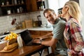 Cheerful couple enjoys a light-hearted moment in their sunny kitchen, working on laptop surrounded by a healthy breakfast Royalty Free Stock Photo