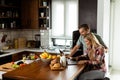 Cheerful couple enjoys a light-hearted moment in their sunny kitchen, working on laptop surrounded by a healthy breakfast Royalty Free Stock Photo