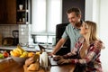 Cheerful couple enjoys a light-hearted moment in their sunny kitchen, working on laptop surrounded by a healthy breakfast Royalty Free Stock Photo