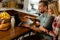 Cheerful couple enjoys a light-hearted moment in their sunny kitchen, working on laptop surrounded by a healthy breakfast Royalty Free Stock Photo