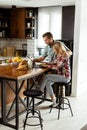 Cheerful couple enjoys a light-hearted moment in their sunny kitchen, working on laptop surrounded by a healthy breakfast Royalty Free Stock Photo