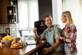 Cheerful couple enjoys a light-hearted moment in their sunny kitchen, working on laptop surrounded by a healthy breakfast Royalty Free Stock Photo