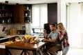 Cheerful couple enjoys a light-hearted moment in their sunny kitchen, working on laptop surrounded by a healthy breakfast Royalty Free Stock Photo