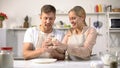 Cheerful couple having fun with dough at kitchen, romantic date for beloved