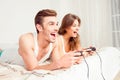 Cheerful couple in love playing video games with joysticks on the bed Royalty Free Stock Photo