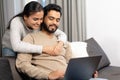 Cheerful couple in love spending leisure time online with a laptop at home. Young woman and man looking at the laptop Royalty Free Stock Photo