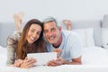 Cheerful couple lying on bed using their tablet pc Royalty Free Stock Photo