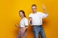 Cheerful couple man and woman dancing against colorful orange studio wall banner background Royalty Free Stock Photo