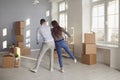 A cheerful couple is playing with a moving box in a bright room of a new house. Royalty Free Stock Photo