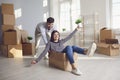 A cheerful couple is playing with a moving box in a bright room of a new house. Royalty Free Stock Photo