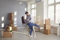 A cheerful couple is playing with a moving box in a bright room of a new house. Royalty Free Stock Photo