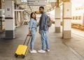 Cheerful couple at a railway station waiting for the train on the platform, arriving at the destination Royalty Free Stock Photo