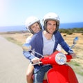 Cheerful couple riding scooter by the seaside Royalty Free Stock Photo