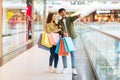 Cheerful Couple Shopping Pointing Finger Aside Holding Bags In Mall Royalty Free Stock Photo