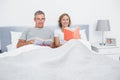 Cheerful couple sitting in bed reading books Royalty Free Stock Photo