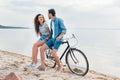 cheerful couple sitting on bicycle on beach