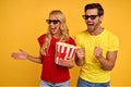 Cheerful couple two friends guy girl in t-shirts 3d glasses isolated on yellow background. People in cinema, lifestyle concept.