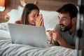 Cheerful couple using a laptop lying on their bed Royalty Free Stock Photo