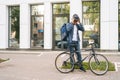 Cheerful courier male getting out of client apartment, sitting on bicycle and riding off to next delivery.