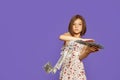 Cheerful and crazy European teenage girl throws money in her hands on a purple background