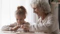 Cheerful curious small girl learning playing checkers with granny. Royalty Free Stock Photo