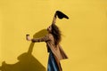 Girl with a cup of coffee on a sunny day near the yellow wall