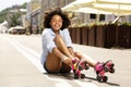 Cheerful curly girl smiling while putting on roller skates