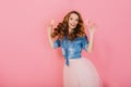 Cheerful curly girl in trendy skirt holding delicious donuts and rejoices at the end of diet. Portrait of jumping long