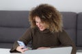 Cheerful curly woman browsing mobile app on smart phone. Happy Ukrainian female person recevied good news on online