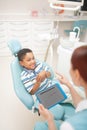 Cheerful cute boy smiling while talking to his dentist